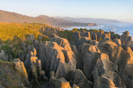 Pancake rocks at sunset with sunlit cliffs, rocks and ocean coastline. Nature landscape. West Coast, New Zealandの写真素材