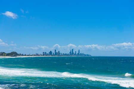 Beautiful ocean with soft waves and modern cityscape on the background. Gold Coast, Australiaのeditorial素材