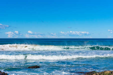 Ocean seascape with powerful waves and clear blue sky on sunny dayの写真素材