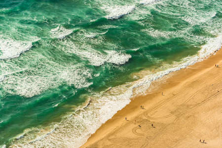 Aerial view of tropical sandy beach and sea, ocean waves with unrecognizable people on the beachの写真素材