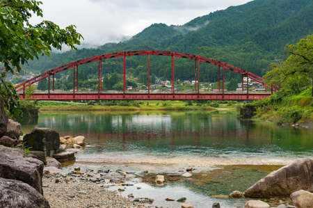 Japanese countryside landscape with bright red bridge over Kiso river. Kiso valley, Nagano, Japanのeditorial素材