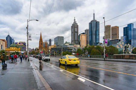 Melbourne, Australia - April 21, 2017: Bright yellow taxi driving on Princes Bridge with Melbourne CBD cityscape on the backgroundのeditorial素材