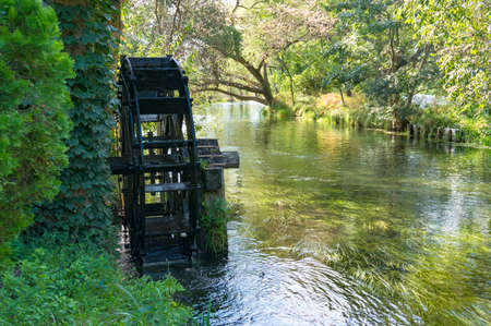 Water mill wheel on river. Water power and renewable energy traditional machineryの写真素材
