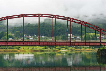 Bright red arch bridge over picturesque river in Japanese countryside. Kiso valley, Nagano, Japanのeditorial素材