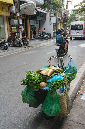 Hanoi, Vietnam - August 12, 2017: Bicycle loaded with groceries, herbs and gum boots on top. Vietnam street lifeのeditorial素材