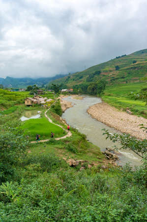 SaPa, Vietnam - August 16, 2017: Aerial view of Vietnamese countryside with tourist and local women guide walking the roadのeditorial素材
