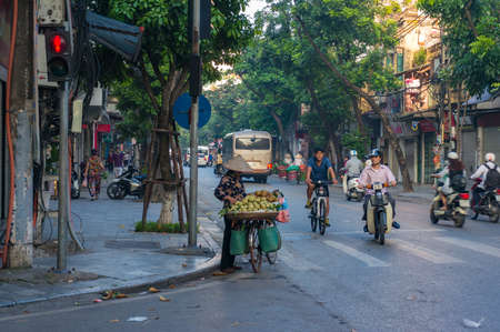 Hanoi, Vietnam - August 21, 2017: Street vendor selling fruits from her bicycle at the kerbside of the roadのeditorial素材