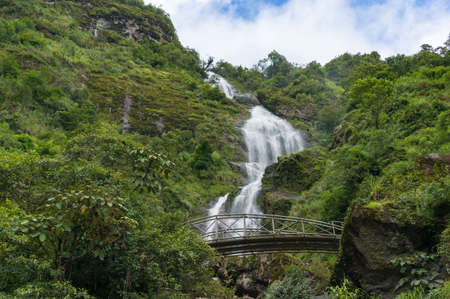 Silver waterfall with arch bridge on sunny day. Nature landscape backgroundの写真素材