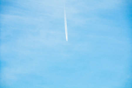 Air plane flying high with white trail against blue sky on the backgroundの写真素材