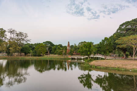 City park in Ayutthaya with river and arch bridge with ruins of ancient temple on the backgroundの写真素材