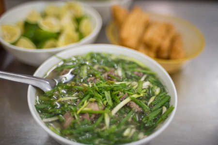 Pho soup served with plenty on spring onions. Traditional Vietnamese cuisine background