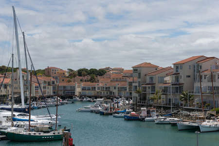 Cape St Francis, South Africa - January 26, 2019: Fishing boats and yachts at harbour with residential houses with water viewのeditorial素材