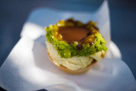 Australian traditional meat pie with mashed potatoes, green peas and gravy in pastry case
