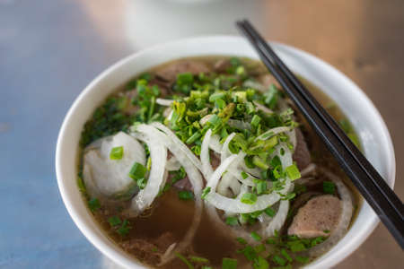 Close up of traditional Vietnamese Pho soup in a bowl with wooden chopsticks