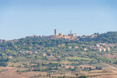 Picturesque Italian landscape with typical Medieval town with towers on the hill and farmlands around. Tuscany, Italyの写真素材