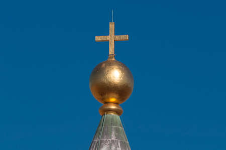 Golden cross with blue sky on the background. Religious symbol conceptのeditorial素材
