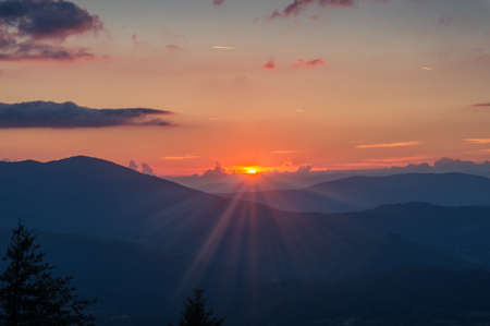 Beautiful sunset in the mountains nature background. Sun rays, sun beams in the Alps, Italyの写真素材