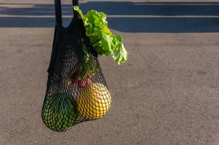 Fresh farmers produce in black mesh string bag. Environmentally friendly reusable shopping bag...