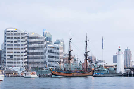 Sydney, Australia - November 22, 2014: Replica of James Cook HMB Endeavor Tall Ship in Darling Harbour with Sydney cityscape on the background on blue hour in the evening のeditorial素材