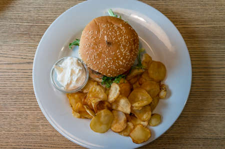 Overhead view of burger with french fries on white plate on wooden tableの写真素材