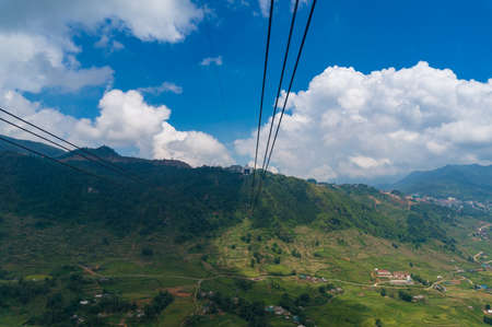 Cable car riding over green mountain valley with rice terraces. Travel adventures backgroundの写真素材