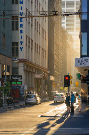Melbourne, Australia - December 7, 2016: Modern urban street scene with traffic and pedestrians at sunset with dust particles in the air, urban air pollutionのeditorial素材