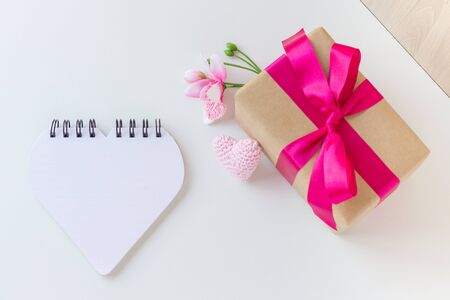 Happy Women's Day, Happy Mother's Day, Happy Valentine's Day and Happy Birthday. A flower, a crochet heart, a beautiful gift wrapped in a pink ribbon and a notebook. White background. Copy space.の写真素材