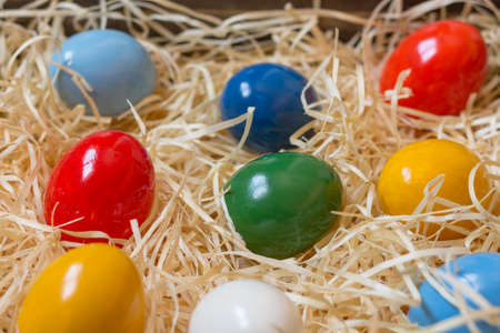 Colorful painted easter eggs in a wooden box with straw. Closeup.