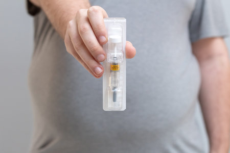 Obese young man holds an anticoagulant syringe to apply after bariatric surgery. On the syringe is written: sale by prescription.の写真素材