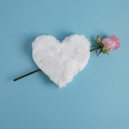 Valentine's Day concept. A rose runs through a heart made of cotton wool on a blue background. Flat lay.の写真素材