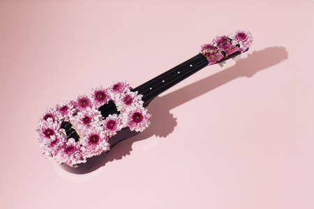 A creative love concept with a guitar made of flowers on a pink background. Valentines or woman's...