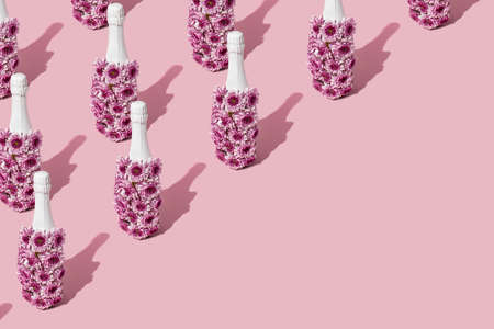 A creative love pattern with a bottle of champagne made of flowers on a pink background. Valentines or woman's day ideaの写真素材