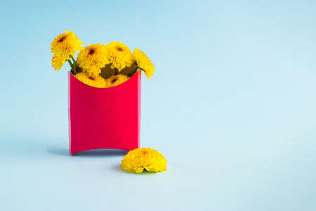 Creative composition with yellow flowers in a french fries box. Valentines or woman's day background design.の写真素材