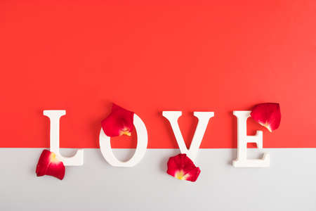Creative composition with LOVE letters on a red and gray background with rose petals. Valentines or...