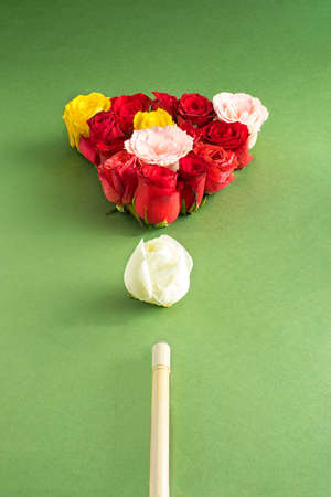 Creative arrangement with colorful flowers on a green background and with a billiard cue. Minimal...
