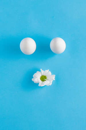 Easter 2021 creative composition with white eggs and a flower on a light blue background. Minimal...