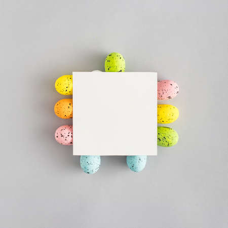 Creative composition with colorful Easter eggs and paper card on gray background. Minimal Spring holidays concept. Creative copy space. Flat lay.の写真素材