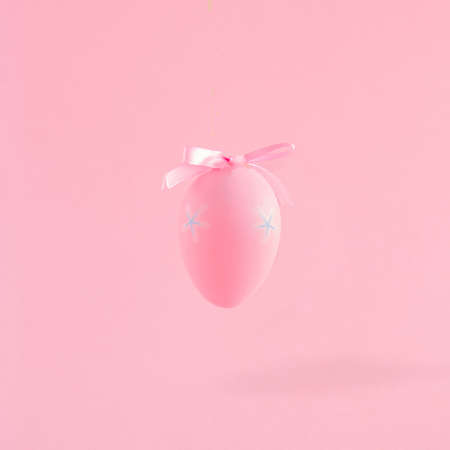 Creative composition with pink Easter egg and bow. Minimal spring Holiday concept. Pastel background.の写真素材
