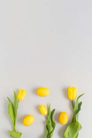Creative composition with yellow flowers and Easter eggs on a gray background. Minimal Spring holidays concept.の写真素材