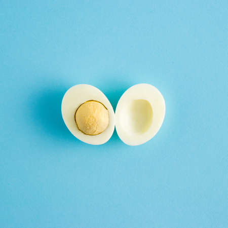 Creative Easter art concept with slices of natural egg and egg yolk on light blue background. Minimal holiday spring conceptの写真素材