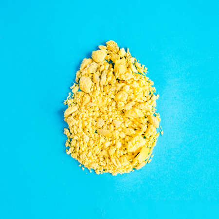 A creative Easter concept with an egg shape made from the yolk of a natural egg on a light blue background. Minimal holiday and food conceptの写真素材