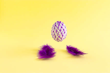 The creative Easter concept made of purple fins and natural eggs with purple stickers levitates above on a yellow background. Minimal holiday or spring concept.の写真素材