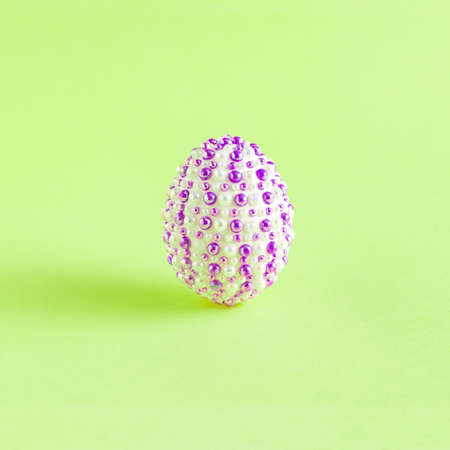 Creative Easter concept made of natural white eggs with purple stickers on a light green background. Minimal holiday or spring concept.の写真素材