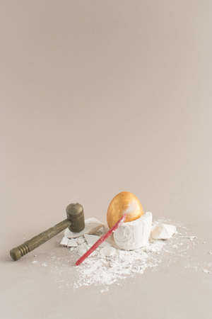 Creative composition with Easter golden egg, hammer, nail and old barrel with treasure. Minimal...