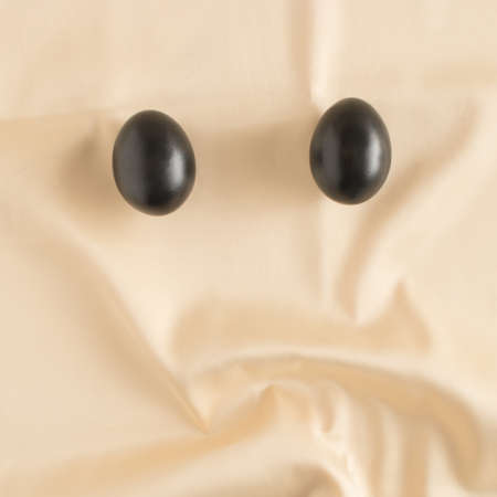 Luxury Easter composition with black eggs on a golden satin background. Minimal luxury Easter concept. Flat lay.の写真素材