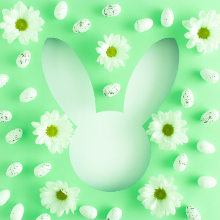 Minimal Easter concept with flowers and eggs on light green background. Creative copy space like bunny head shape. Spring holiday layout. Flat lay.の写真素材