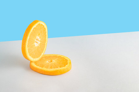 Creative summer composition with two slices of fresh orange on a blue and gray background. Minimal fresh nature or food concept.の写真素材