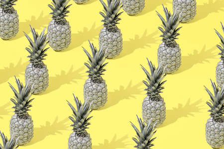 Creative summer pattern background with gray pineapple on a yellow background. Minimal style. Creative summer or food concept.の写真素材