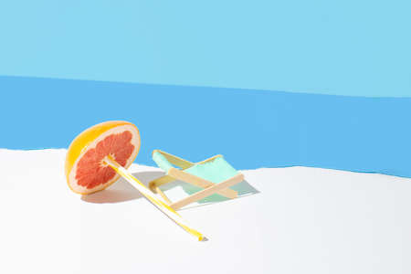 Tropical beach concept made of fresh red grapefruit, straws and beach chairs. Creative minimal...