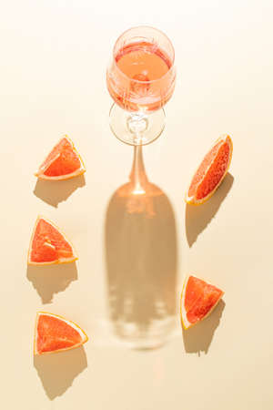 Summer composition with a fresh cocktails, and pieces of fresh grapefruit. Sunny day shadow. Minimal summer, tropical concept.の写真素材
